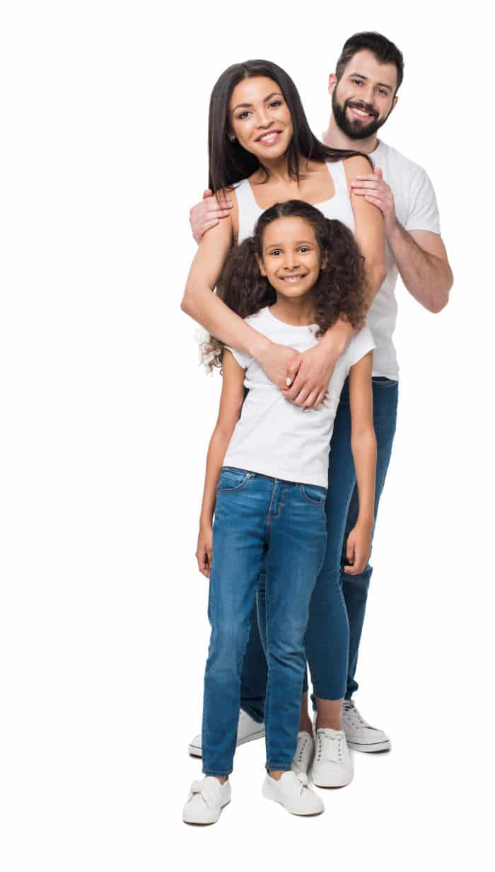 a family of three with white shirts and blue pants smiling to show their braces free smile