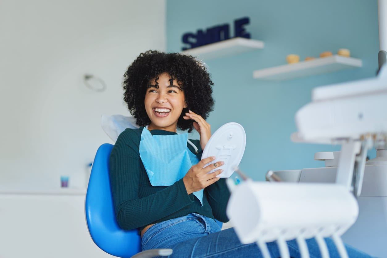 a happy orthodontic patient in a chair inspecting her teeth