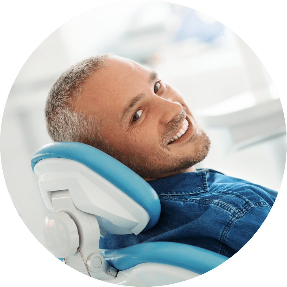 an adult male sitting on an orthodontic chair and looking back with a smile
