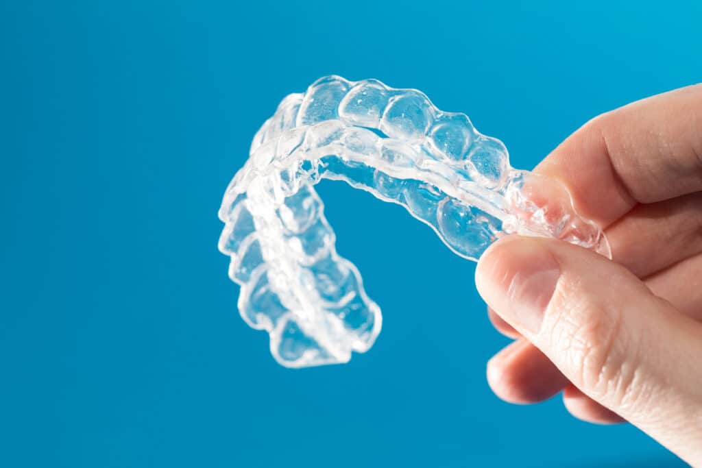 Close up of person holding clear aligner trays with 3 fingers