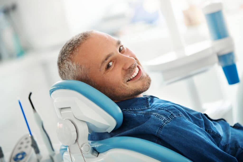 A cheerful early 40's male patient happily smiling to the camera after his dental procedure