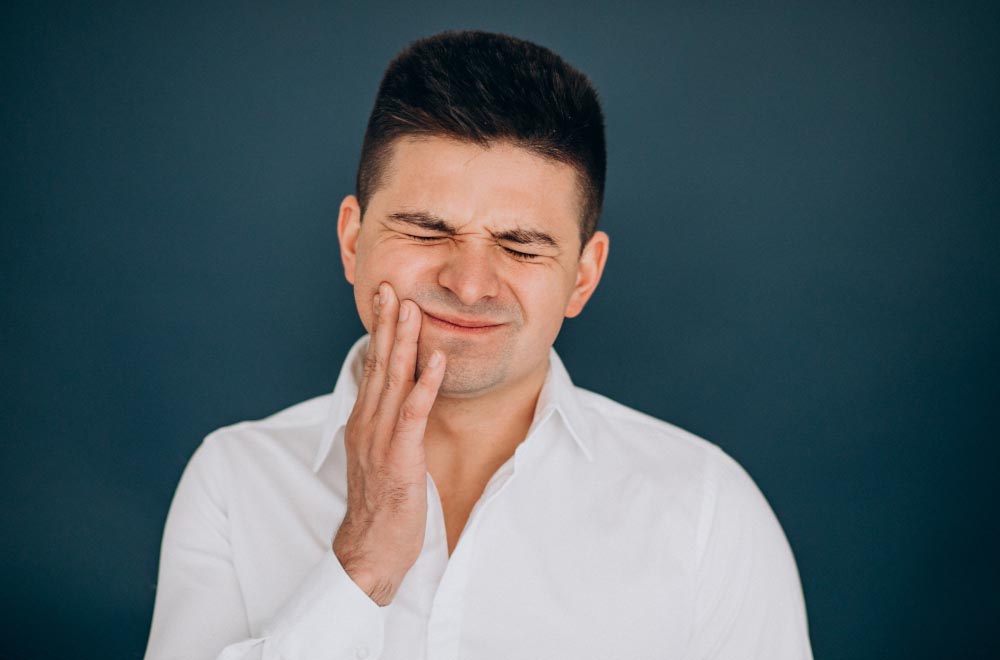 A man holding his jaw in pain from his wisdom teeth