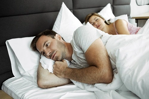 Man in bed can not sleep because Sleep Apnea