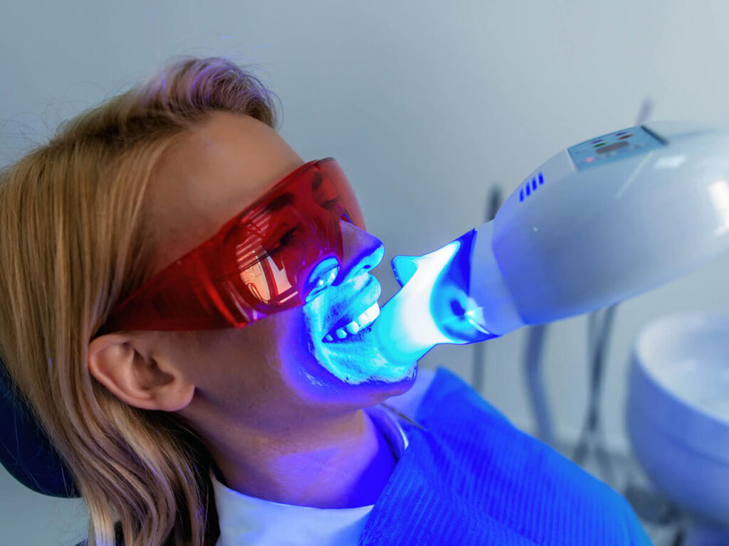 Woman undergoing a teeth whitening procedure with a blue light device