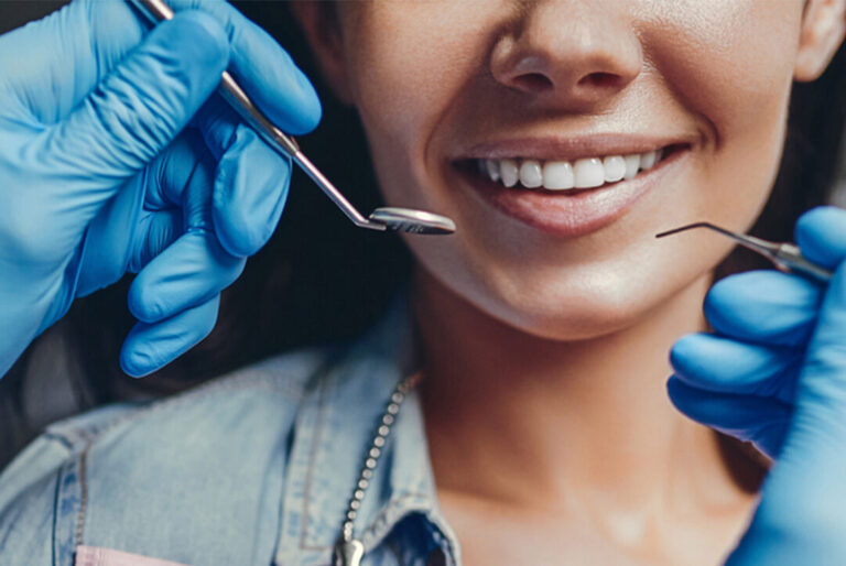 Close-up of a person receiving a dental checkup, with a gloved hand holding a dental mirror